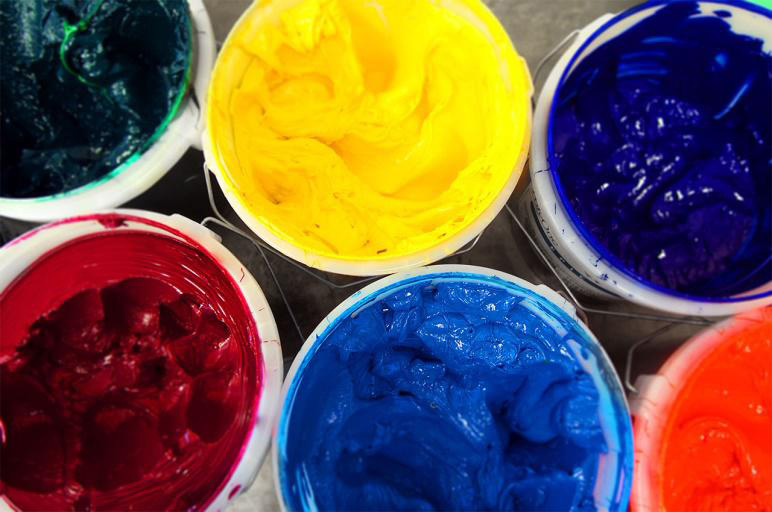 overhead close-up buckets of yellow, red, blue, and green screen printing plastisol inks